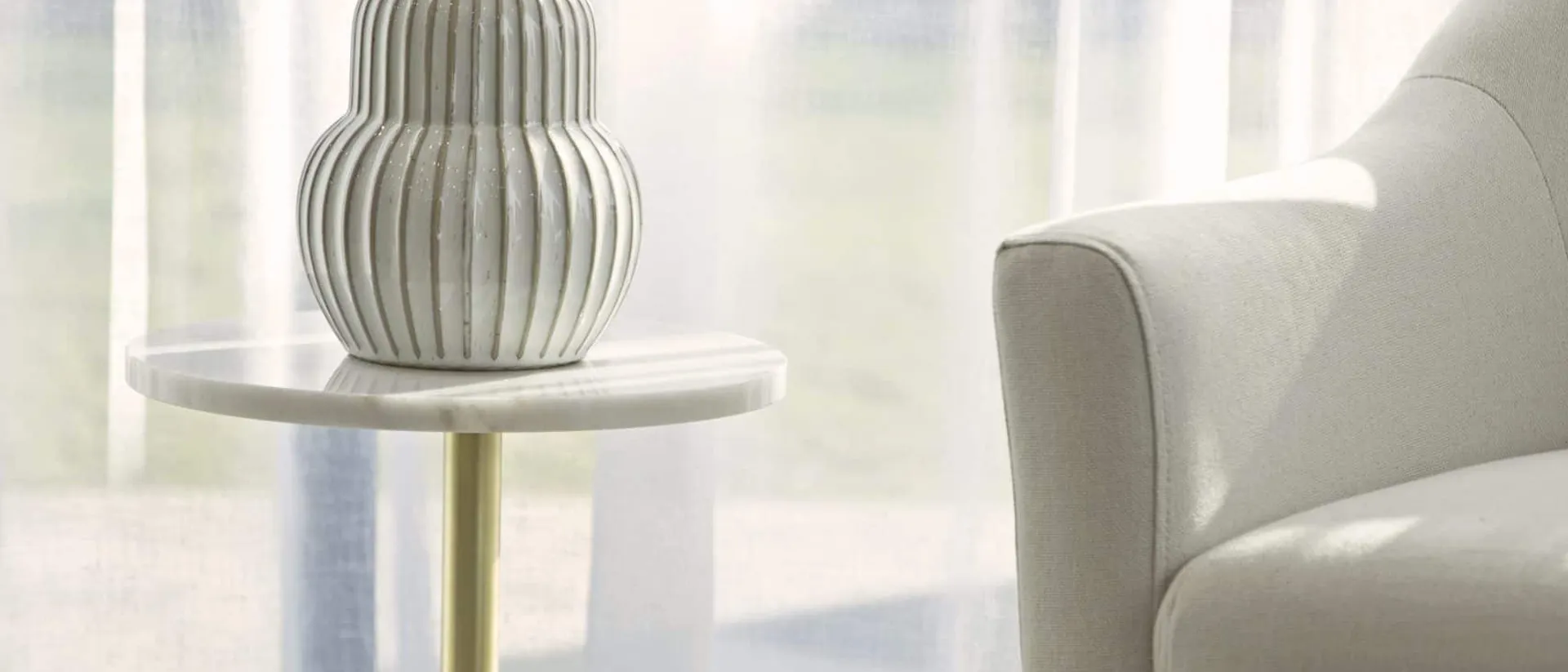 Dolomites — white armchair, brass side table, sheer curtains
