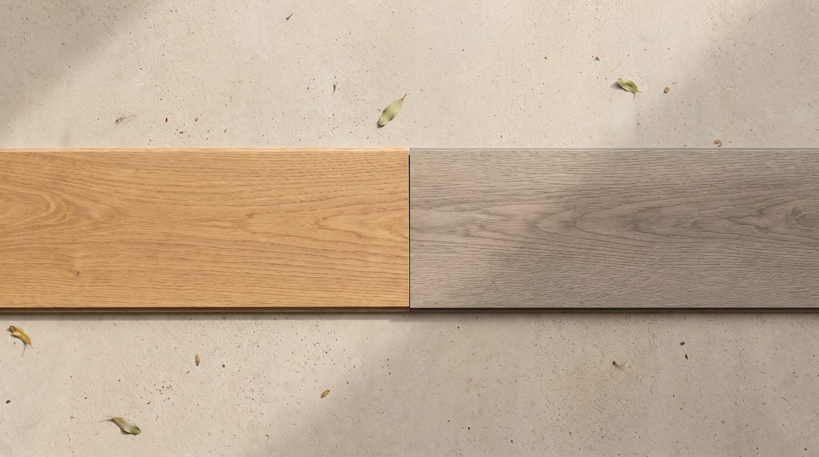 An engineered oak plank and a grey hybrid plank laid side by side on a pale concrete floor