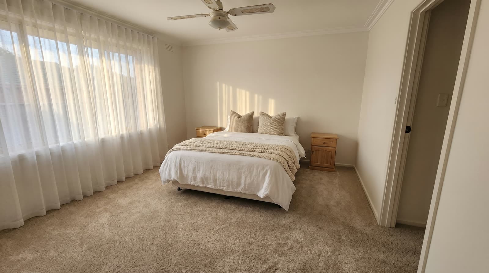 The same bedroom after renovation, with plush new oatmeal wool carpet and styled bedding
