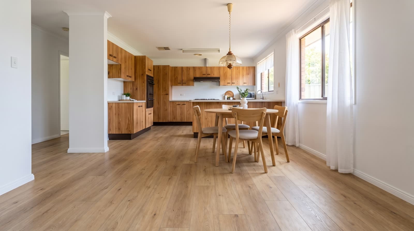 The same dining area after renovation, with wide-plank oak-look hybrid flooring