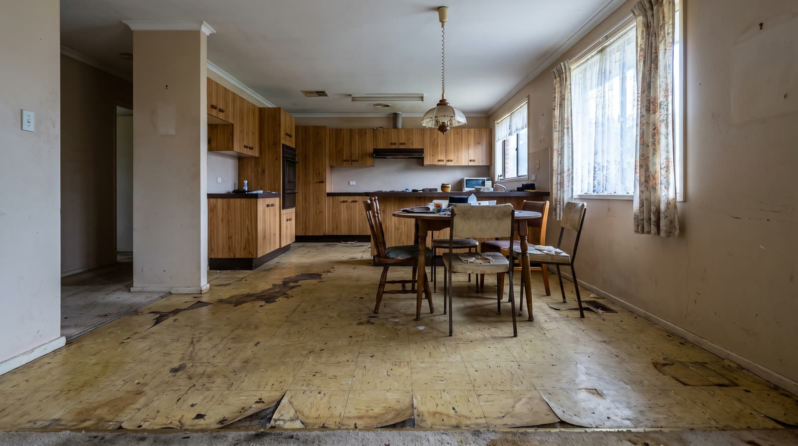 Dining area before renovation — peeling sheet vinyl and a dated kitchen