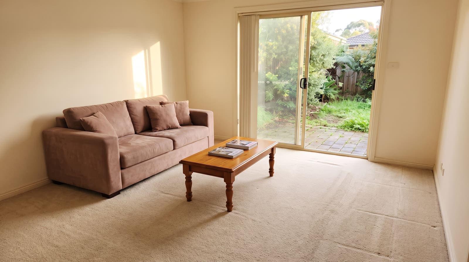The same living room before renovation, with dated beige carpet, magnolia walls and older furniture