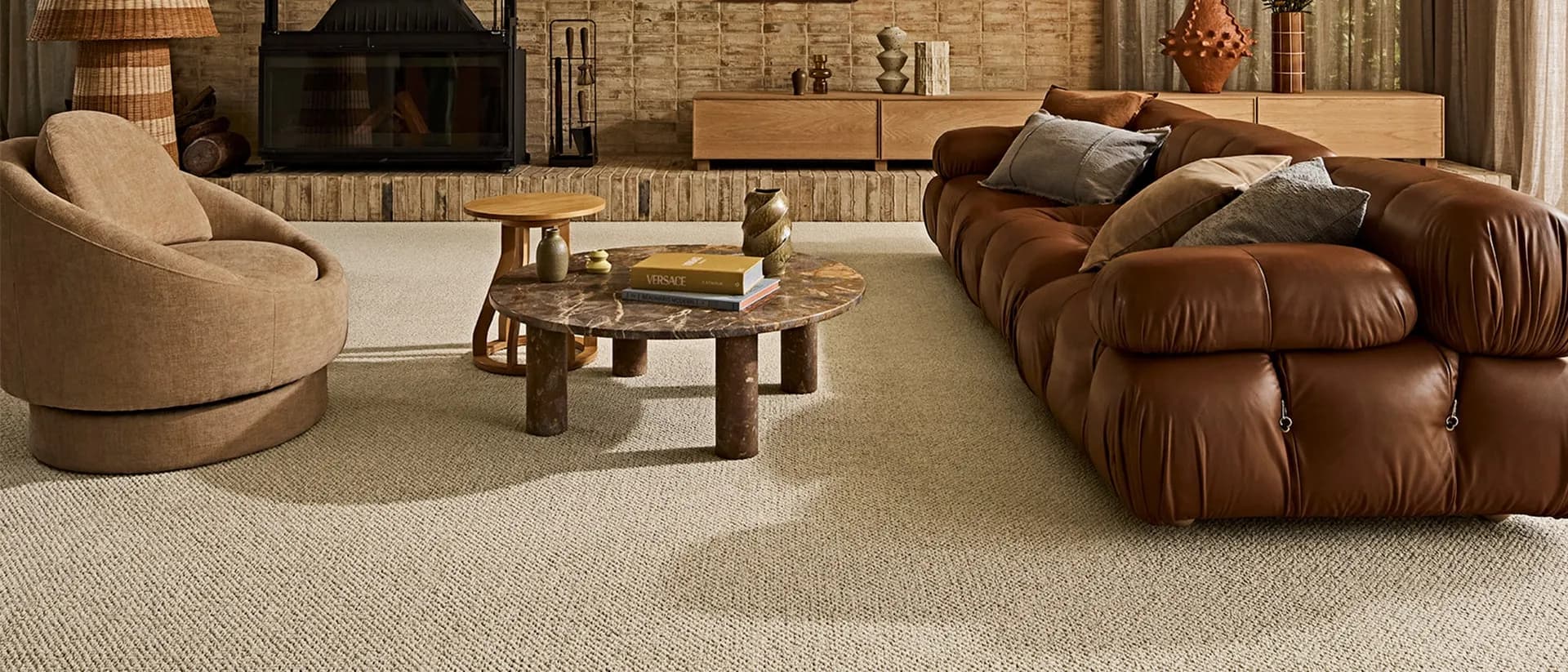 Stonefields — warm living room, brown leather sofa, brick fireplace wall