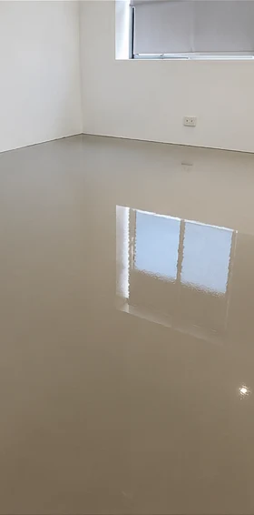 Self-levelling compound flowed out across the room, still wet and reflecting the window.